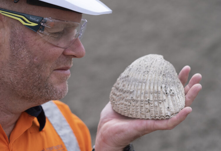 Central Interceptor executive programme director shayne cunis holding a giant historic shell